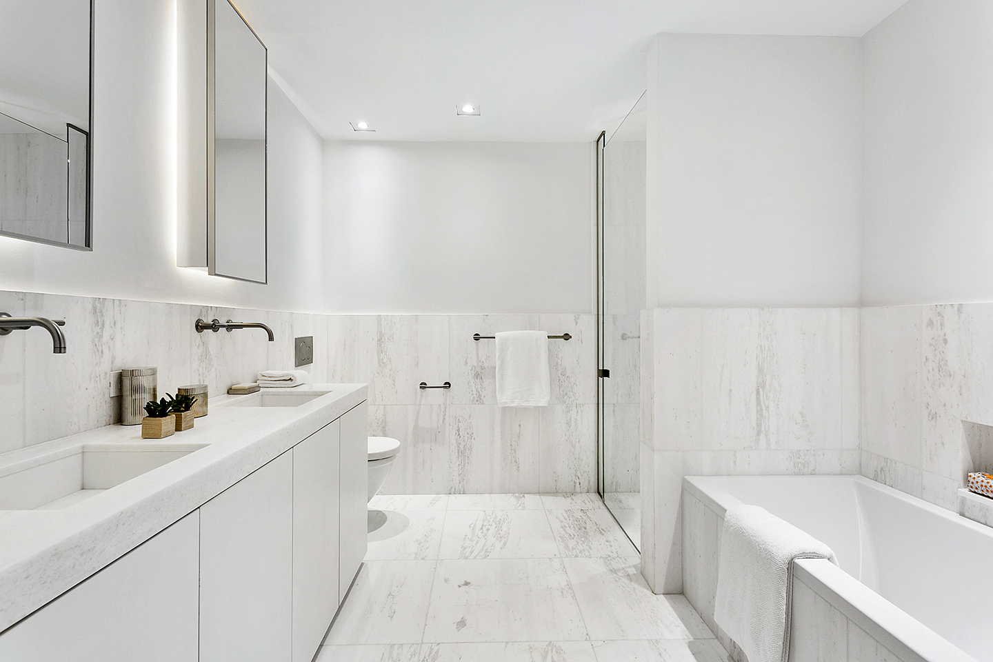 Finely honed marble countertops and wall cladding in the master bathroom by Piet Boon